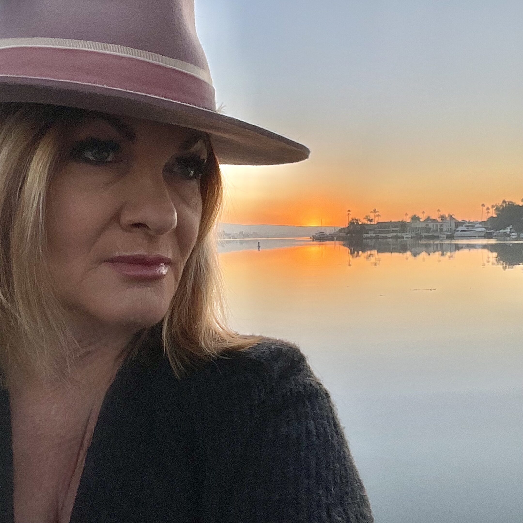 Woman in hat at calm waterfront sunset
